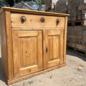 A restored antique pine sideboard featuring a single drawer over a double cupboard base.