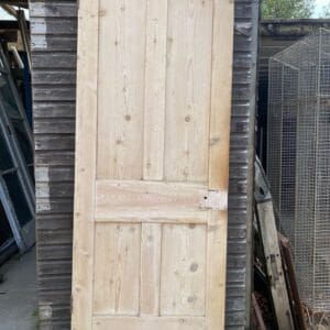 A traditional stripped pine Victorian four panel door shown from the front.